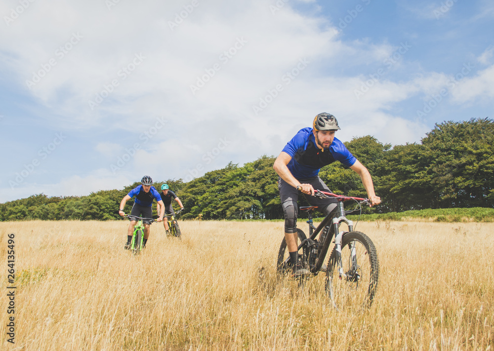 Mountain bikers ride through field in English countryside