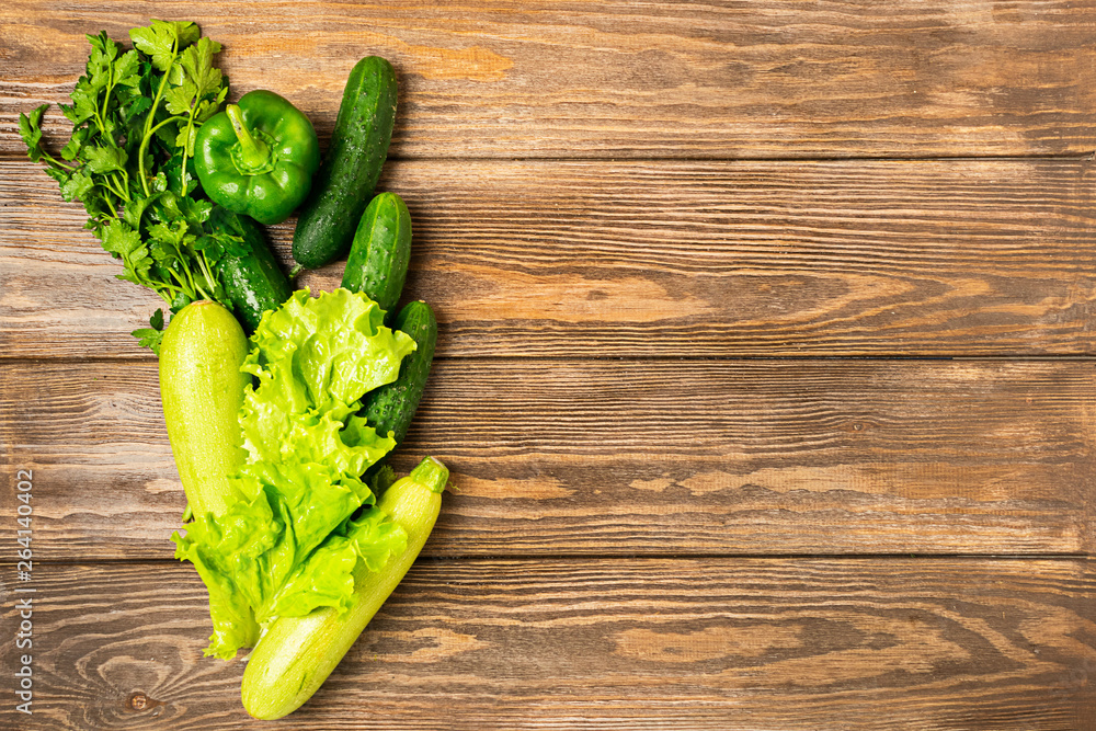 Fresh green vegetables zucchini cucumber greens pepper wooden background. Healthy food vegetarianism. Vertical frame. Fresh green vegetables zucchini cucumber greens pepper wooden background. Healthy food vegetarianism. Vertical frame.