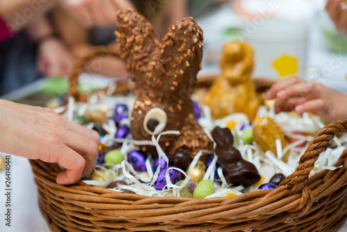many hands reach for sweets candy and chocolate in an Easter egg basket during Easter