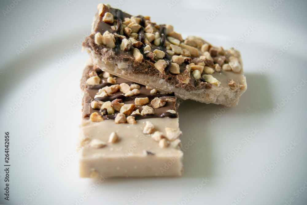 Tile white and black chocolate sprinkled with nuts on plate