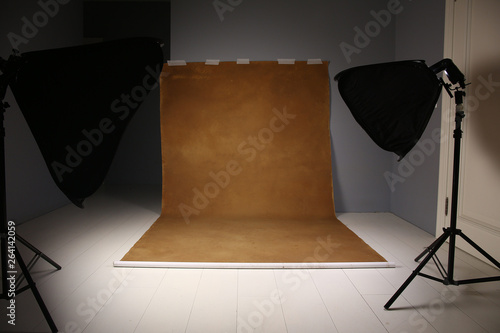 Empty photo studio with lighting equipment. Gray and brwon background