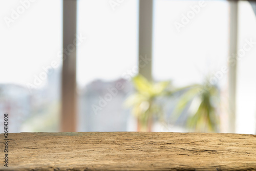 Wood table top on blur of window glass and abstract green from garden with city view in the morning background. For montage product display © kishivan