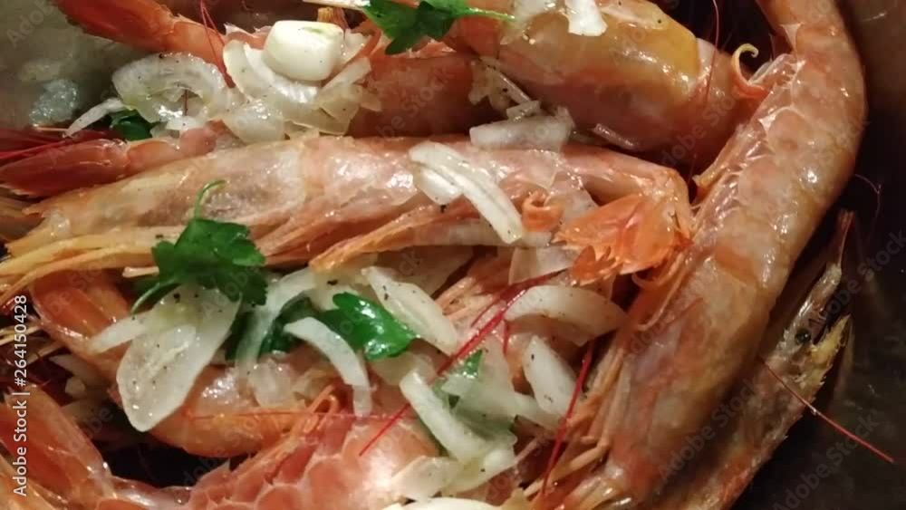 Appetizing close-up on pots filled with large Argentine prawns seasoned with onion, parsley and pepper, ready for cooking. In the background visible flour anchovies for frying. 25 Fps