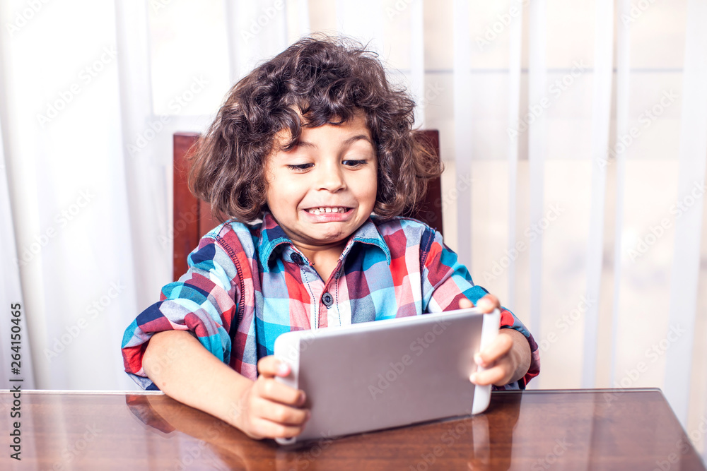 Little boy looking at touch pad at home. Children, technology concept Little boy looking at touch pad at home. Children, technology concept