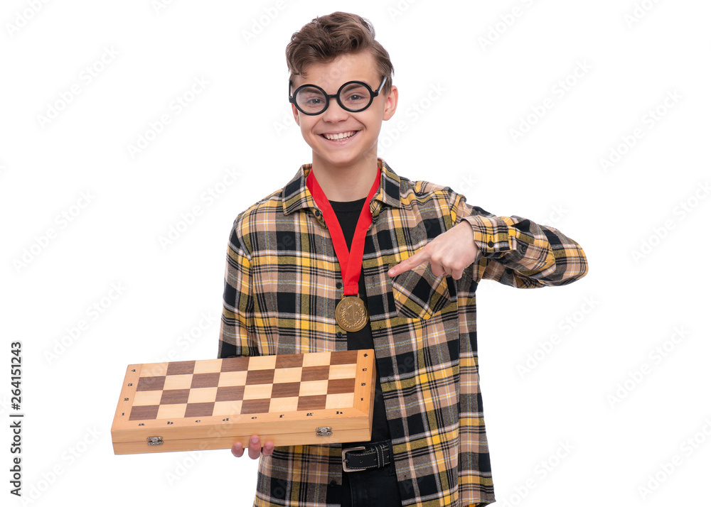 Happy winner. Portrait of Handsome Teen Boy Student in funny eye Glasses holding gold Medal and Chess board. Child isolated on white background. Happy winner. Portrait of Handsome Teen Boy Student in funny eye Glasses holding gold Medal and Chess board. Child isolated on white background.