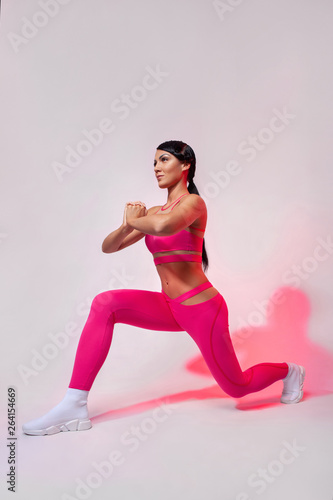 Strong athletic woman, doing exercise on white background wearing sportswear. Fitness and sport motivation.