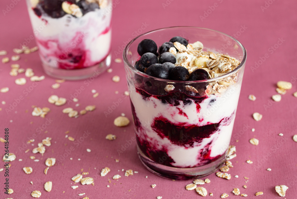 Ice cream with berries and muesli. Ice cream in a glass with currants, berry jam and muesli on a pink background. Close-up. Ice cream with berries and muesli. Ice cream in a glass with currants, berry jam and muesli on a pink background. Close-up.