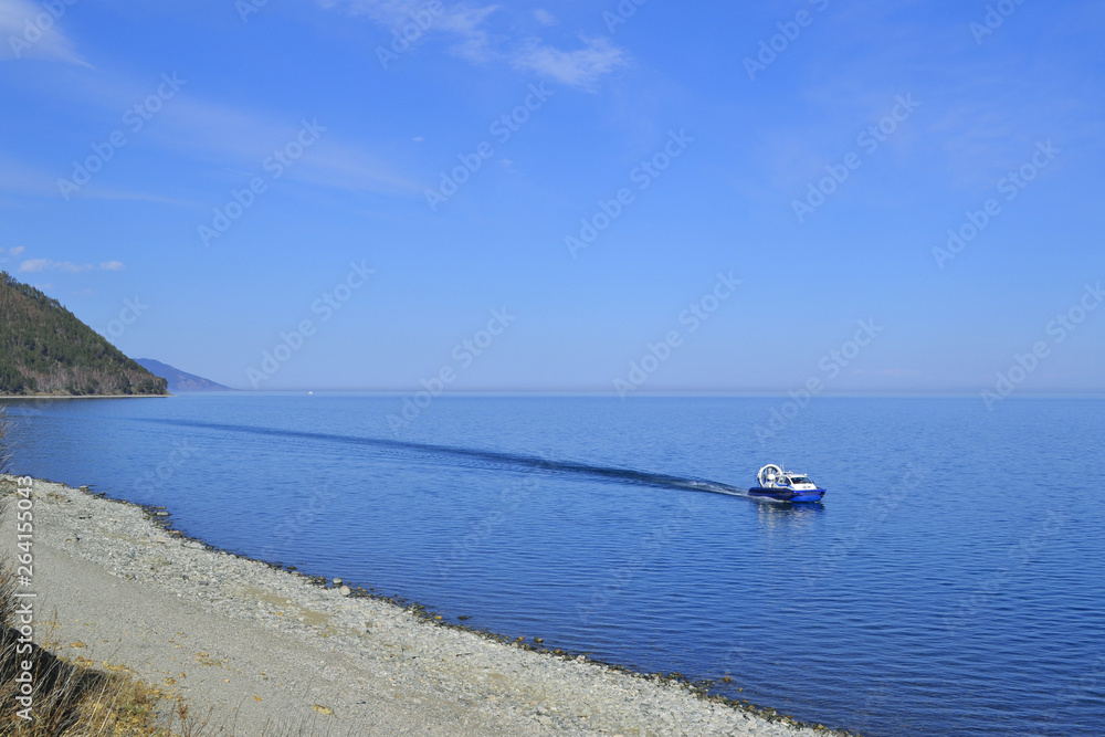 A boat floats on a lake on a sunny day. Beautiful background, free space for text.