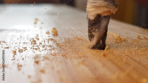 Closeup of drilling into the wood. Metal drill bit make holes in a wooden spruce plank. Wood processing. Carpenter working with self-standing drill. photo