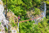 Lady tourist on suspended wooden via ferrata bridge on a route called 