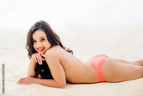 beautiful topless Young woman looking at camera, smiling and relaxing on sandy beach