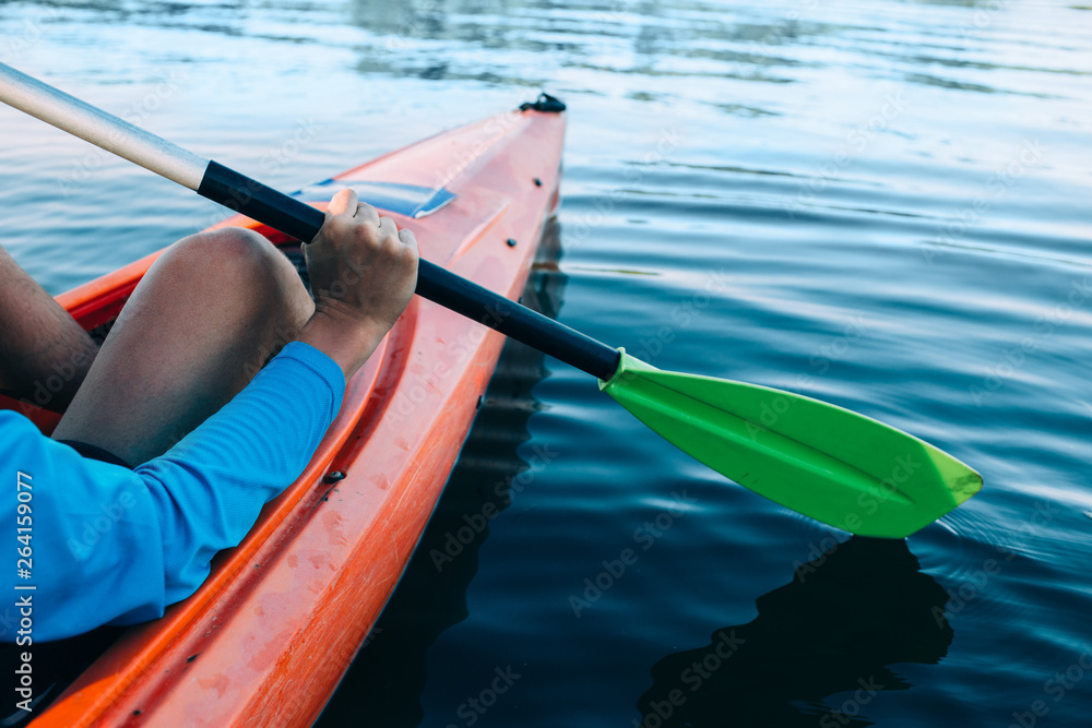 kayaker paddles across a serene lake, focus on the foreground - obrazy, fototapety, plakaty 