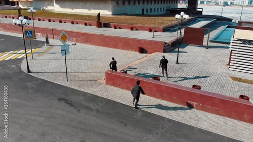 Wallpaper Mural Three athletic young men running on the road and doing tricks. Aerial view Torontodigital.ca