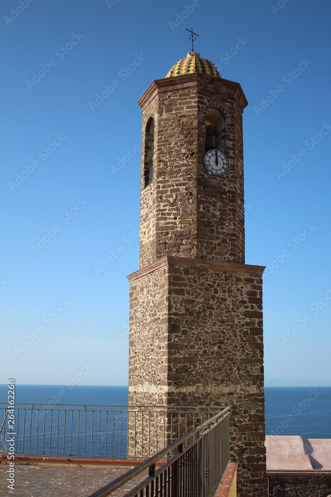 Obraz premium Stone church tower with blue sky and ocean background