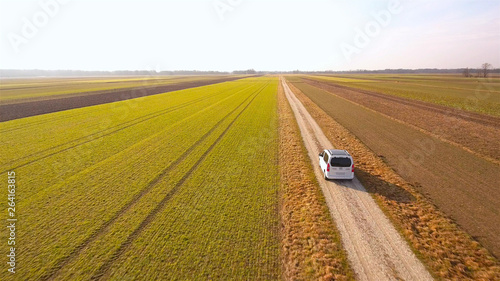 Flying behind a white van driving through farm fields