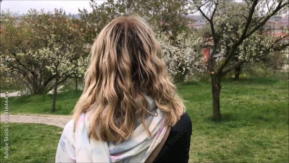 Young woman walking through the blooming trees over Prague cityscape Young woman walking through the blooming trees over Prague cityscape