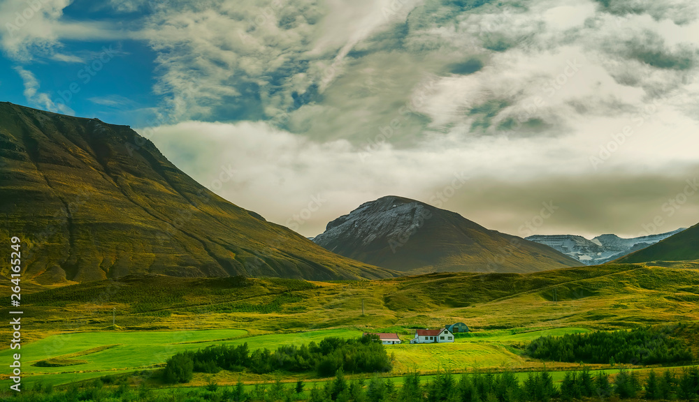 Small houses in the valley among the mountains. Typical Icelandic landscape. A beautiful view of secluded housing.