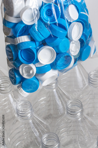 Empty plastic water and a plastic bagg full of caps ready to be recycled