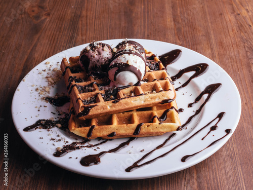 Belgian waffles with ice cream. Chocolate and nuts. wooden table. Rustik