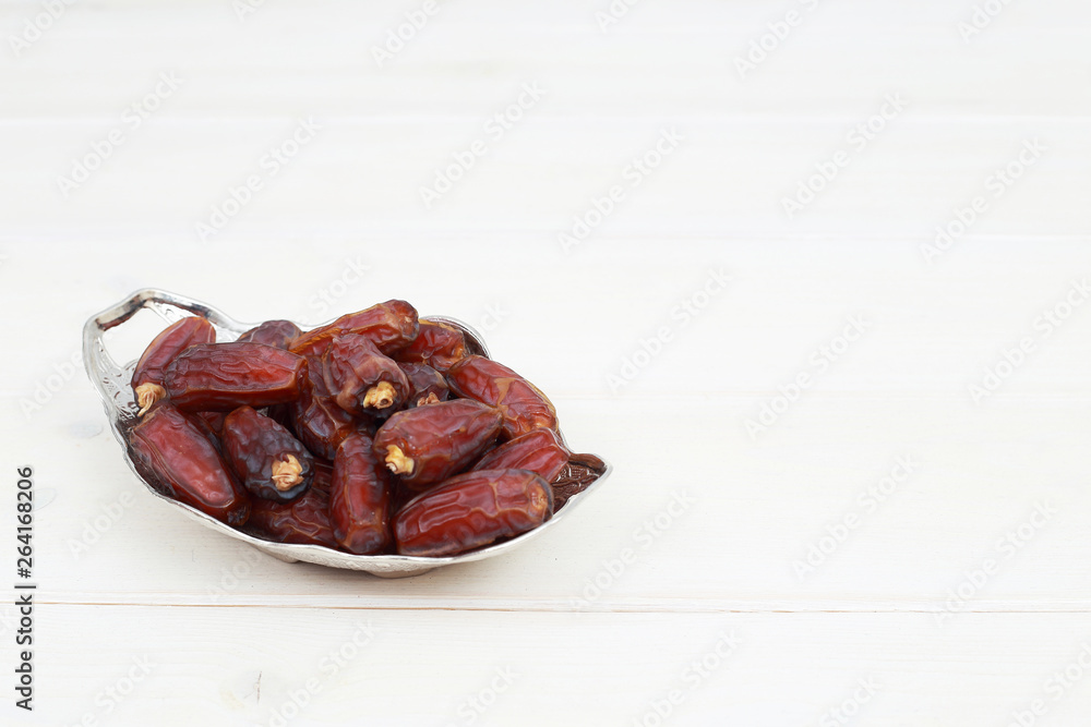 Islamic festival of Ramadan concept. with a delicious tropical dates on a silver plate and shiny rosary on a white wooden table background. Traditional Middle East culture. Ramadan Kareem. Islamic festival of Ramadan concept. with a delicious tropical dates on a silver plate and shiny rosary on a white wooden table background. Traditional Middle East culture. Ramadan Kareem.
