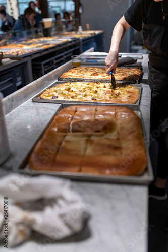 Obraz na plátně Pizzeria al taglio, tavola calda, ristorazione, con cuochi che servono i clienti