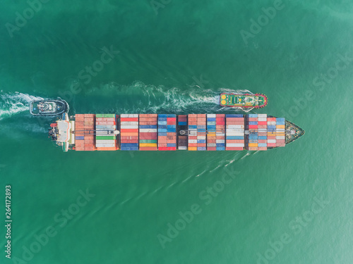 erial top view Tugboat drag container ship full load container to seaport for logistics, import export, shipping or transportation. © Pawinee