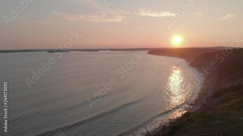 Cinematic drone / aerial footage rotating showing some hills, a forest and sea waves hitting the coast of Kingsburg, Nova Scotia, Canada during summer season photo