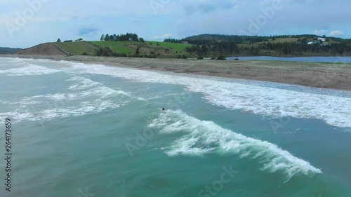 Cinematic drone / aerial footage rotating showing a surfer in the water in Kingsburg, Nova Scotia, Canada during summer season. photo