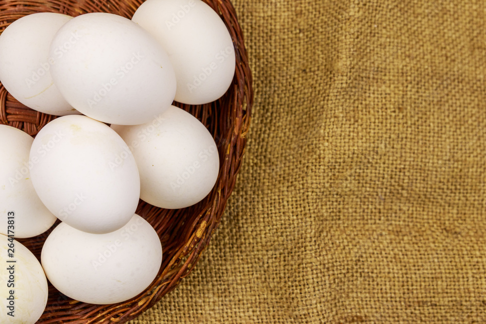 White chicken eggs in wicker basket on sackcloth background White chicken eggs in wicker basket on sackcloth background