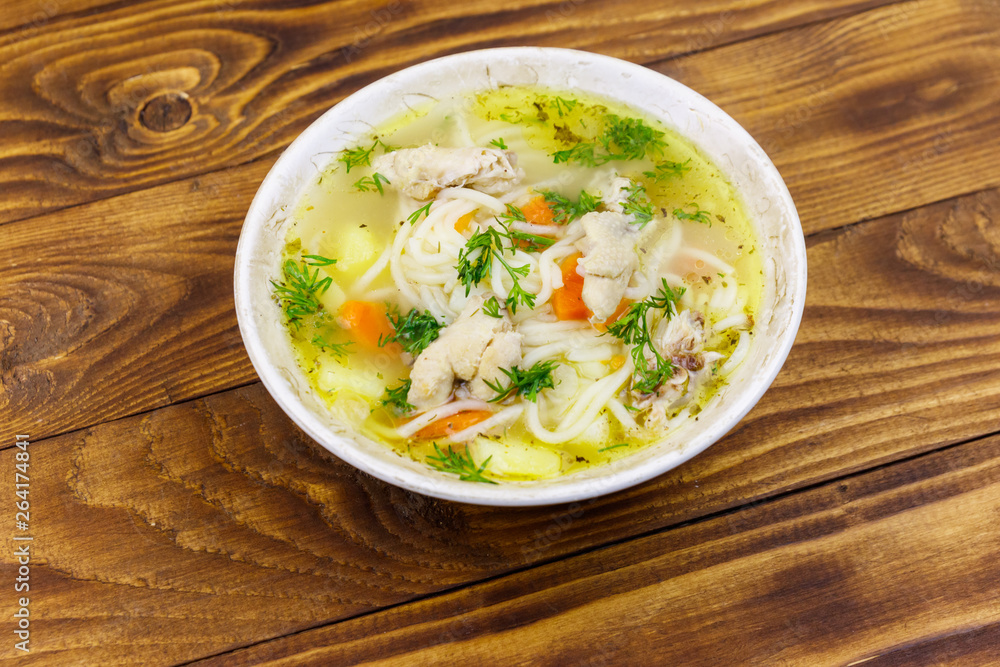Chicken soup with noodles and vegetables on wooden table Chicken soup with noodles and vegetables on wooden table