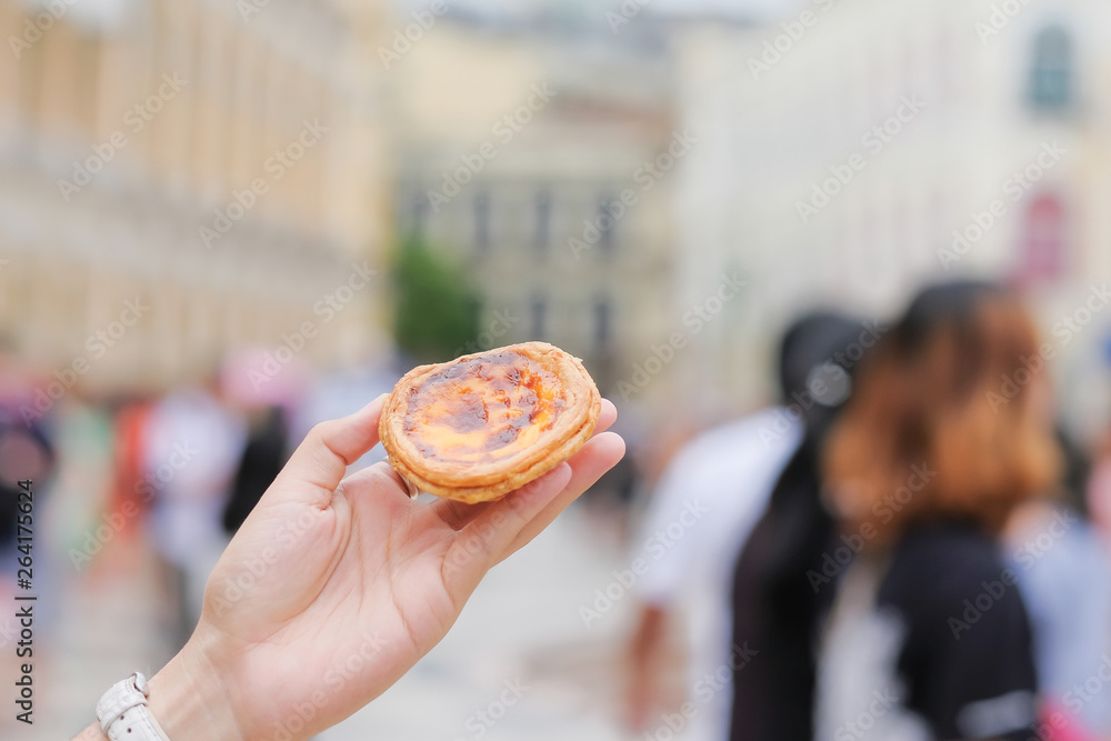 hand holding an Egg tart, famous traditional Portuguese desserts at senado square in Macau. Landmark and popular for tourists attractions hand holding an Egg tart, famous traditional Portuguese desserts at senado square in Macau. Landmark and popular for tourists attractions