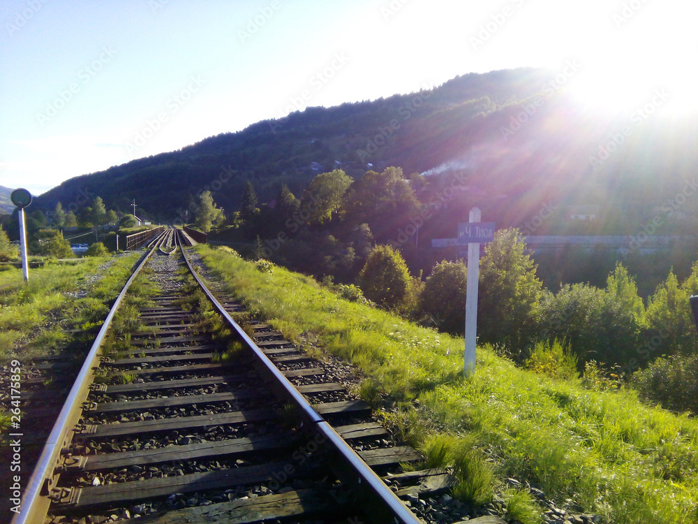 Railway tracks in the mountains in the spring in the sun and grass.