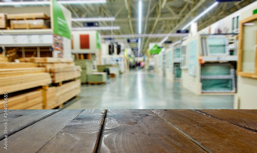 Shop for the sale of building materials. Planks, windows, flooring. In the foreground is the top of a wooden table, counter. Shop for the sale of building materials. Planks, windows, flooring. In the foreground is the top of a wooden table, counter.