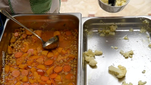 Cook serving healthy food like cooked carrots to pupils in a nursery