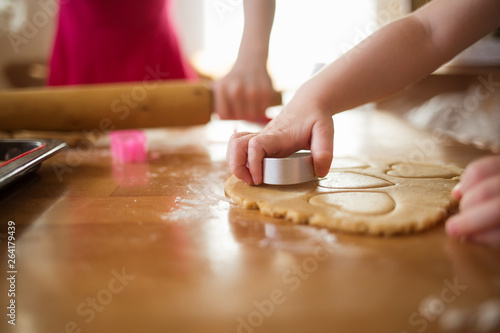 child in the kitchen makes homemade cookies. kid cook at home. girl cuts hearts with a cutter