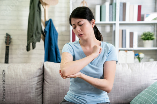 Canvas Print unhappy young asian woman with elbow pain indoors