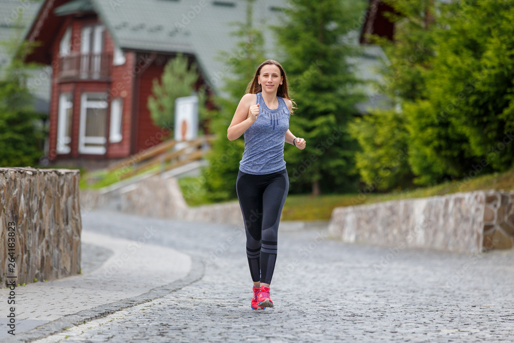 Young woman running in mountain european town in the morning