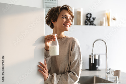 Happy brunette woman drinking milk and looking away Fototapet