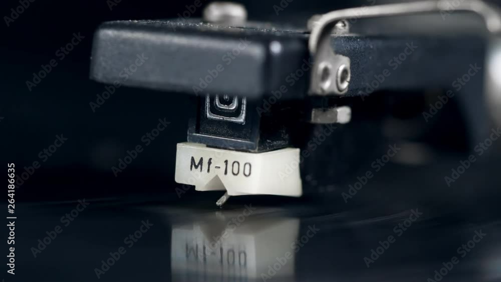 Cartridge and a moving vinyl record in a close up Cartridge and a moving vinyl record in a close up