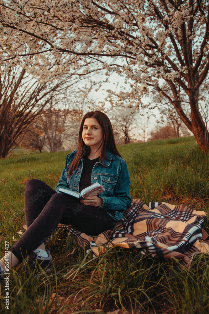 Girl sitting in a park under a tree and reading a book Girl sitting in a park under a tree and reading a book