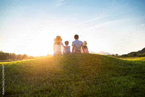 Happy young family sitting on meadow photo