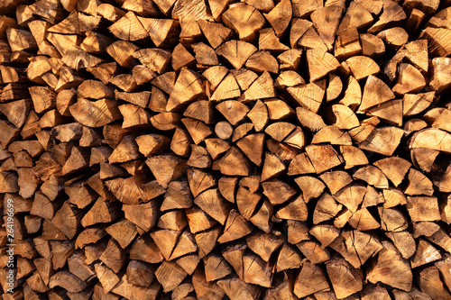 Background of dry chopped firewood  stacked wood trunks for winter heating fireplace.