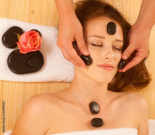 attractive young beautiful woman having facial massage with mineral stone