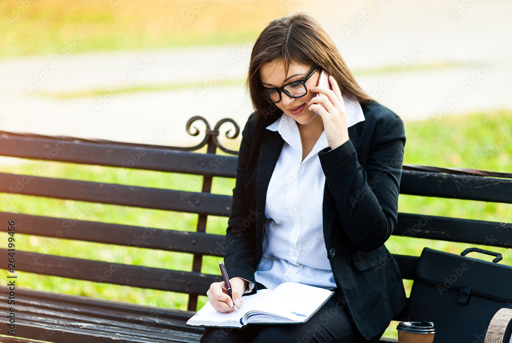 Happy businesswoman calling on mobile phone and taking notes outdoor Happy businesswoman calling on mobile phone and taking notes outdoor