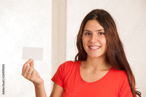 Wallpaper Mural Beautiful young woman in red t shirt holds blank card over white background Torontodigital.ca