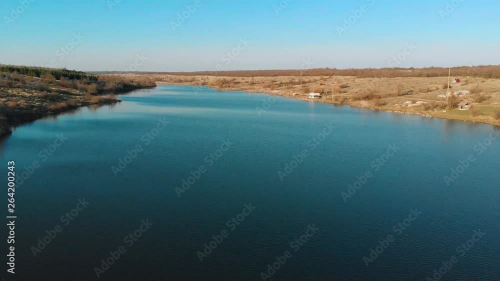 Drone shoot of deep blue lake with fishing and hunting lodges on shore. Wild nature in countryside Drone shoot of deep blue lake with fishing and hunting lodges on shore. Wild nature in countryside