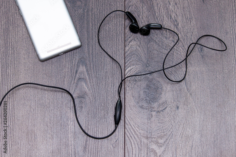 Mobile phone with earphones in shape or heart on wooden background. Flat lay, copy space. Mobile phone with earphones in shape or heart on wooden background. Flat lay, copy space.