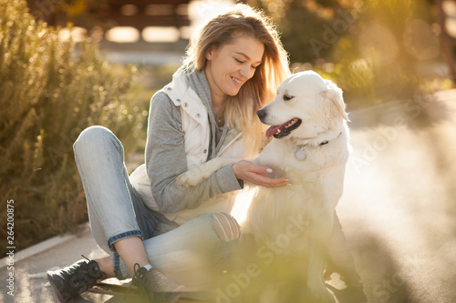 Fototapete beautiful girl with a dog breed Golden Retriever best friends on a walk looking