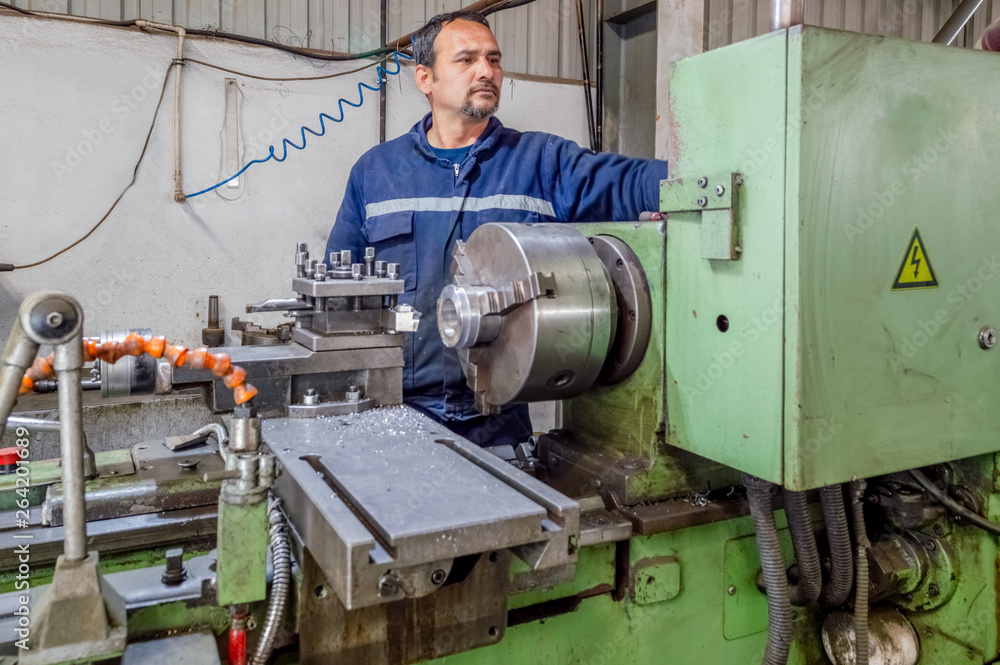 Heavy industrial worker operator working with lathe machine Heavy industrial worker operator working with lathe machine