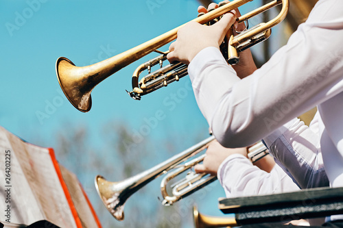 A closeup of several trumpeters playing in a brass band